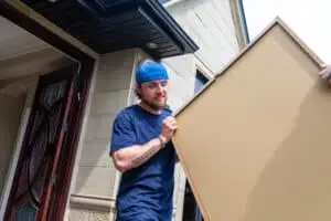 Man carrying large board out of house
