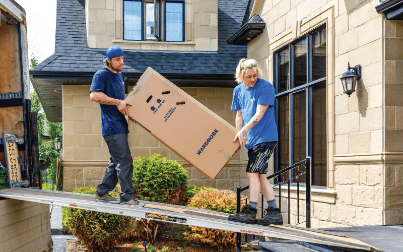 Movers moving a large cardboard box down the ramp