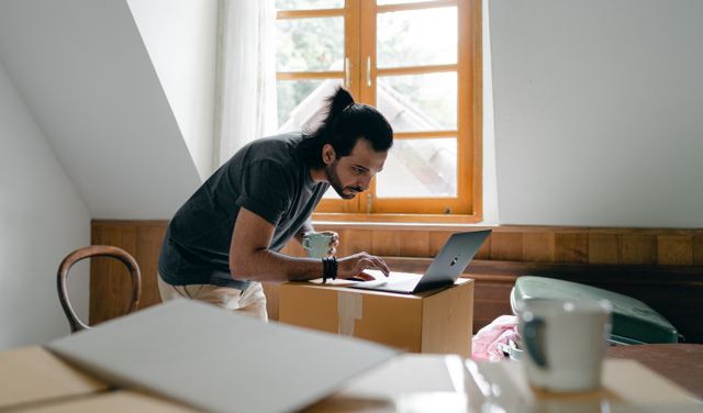 Man working on laptop in sunlit attic room