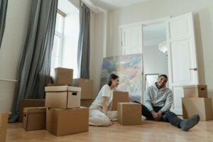 Couple sitting on floor surrounded by moving boxes