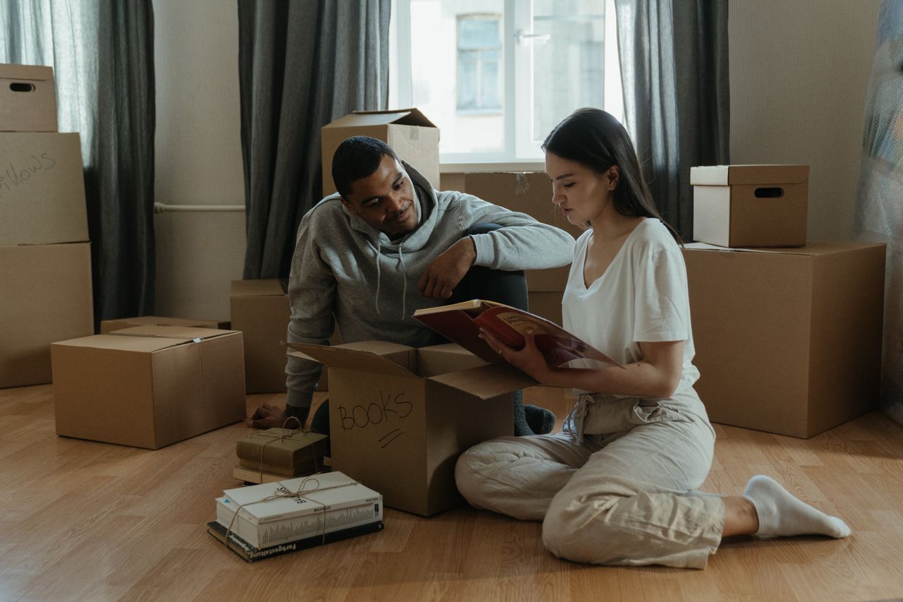 Couple unpacking moving boxes and looking at a photo album in their new home